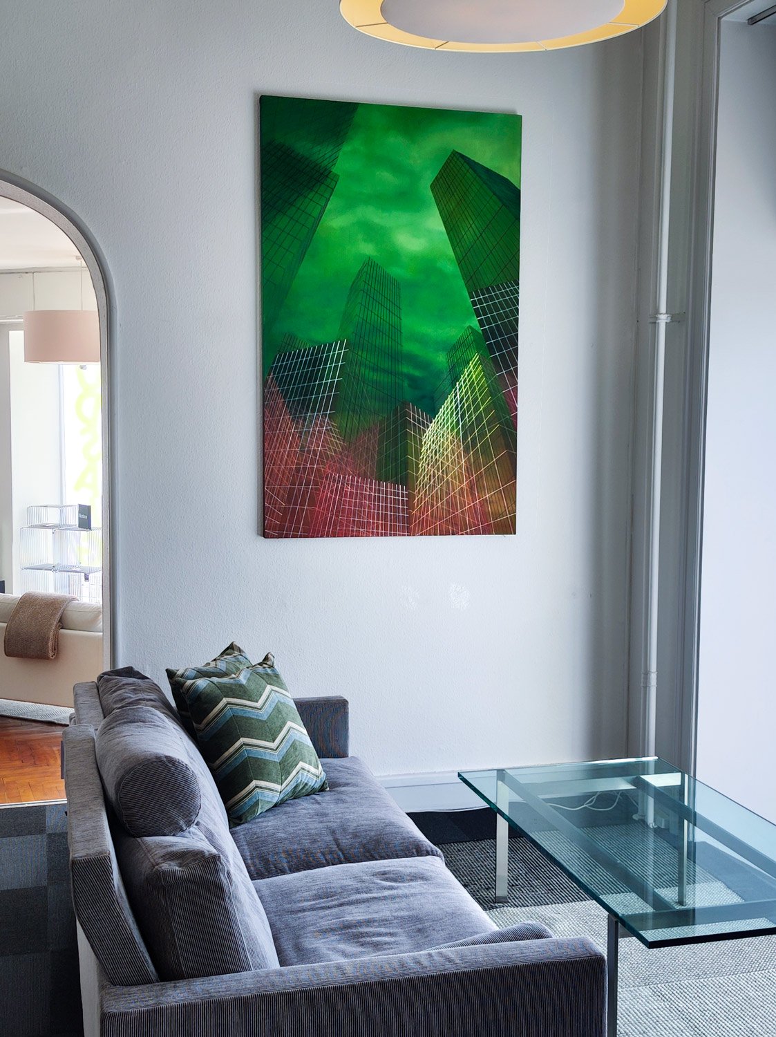 A profound, haunting, and visually compelling original oil painting by Noemi Staniszewska. The artwork critically examines how capitalism structures architecture and directly influences the way we live. Through soaring, transparent gridlines and a dramatic green-to-red palette, Staniszewska captures the imposing essence of modern skyscrapers towering into the ether — serving as monuments to economic force and urban isolation.